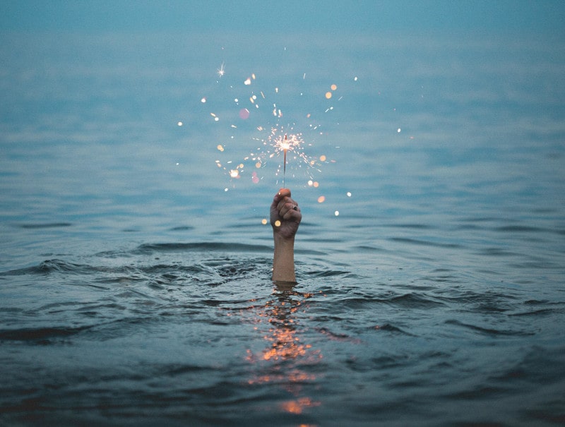 hand coming out of water holding sparkler