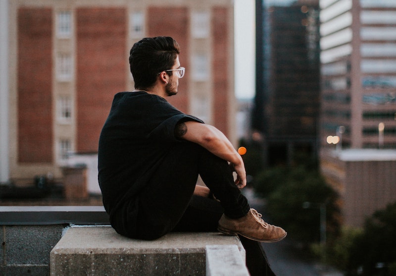 thoughtful man sitting on the edge of a roof